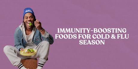 A happy person is seated on a wooden block, taking a bite of broccoli from a plate of food. The background is a solid purple color with white text that reads: "IMMUNITY-BOOSTING FOODS FOR COLD & FLU SEASON."